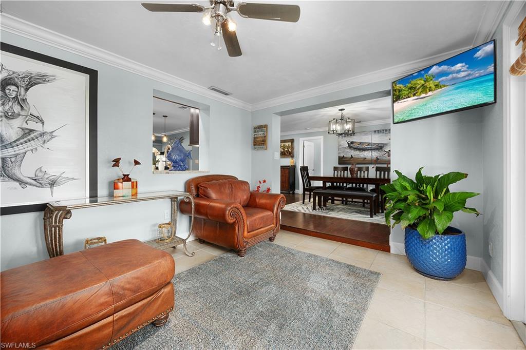 Living area featuring ceiling fan, hanging lights, crown molding, and light tile patterned floors