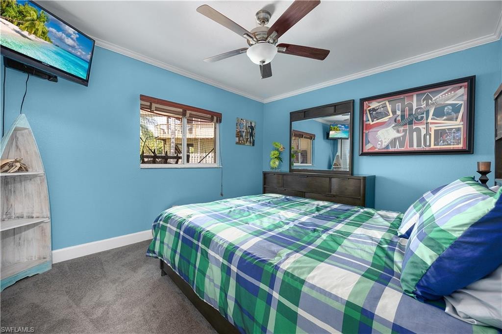 Bedroom featuring dark carpet, ceiling fan, and ornamental molding
