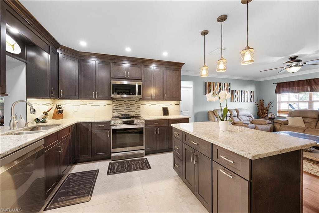 Kitchen with stainless steel appliances, light stone counters, a ceiling fan, open floor plan, and dark wood finish cabinetry