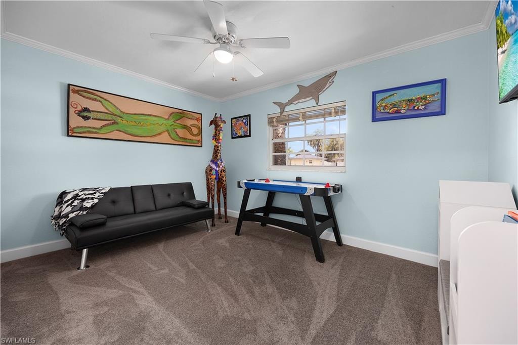 Sitting room featuring carpet floors, crown molding, and a ceiling fan