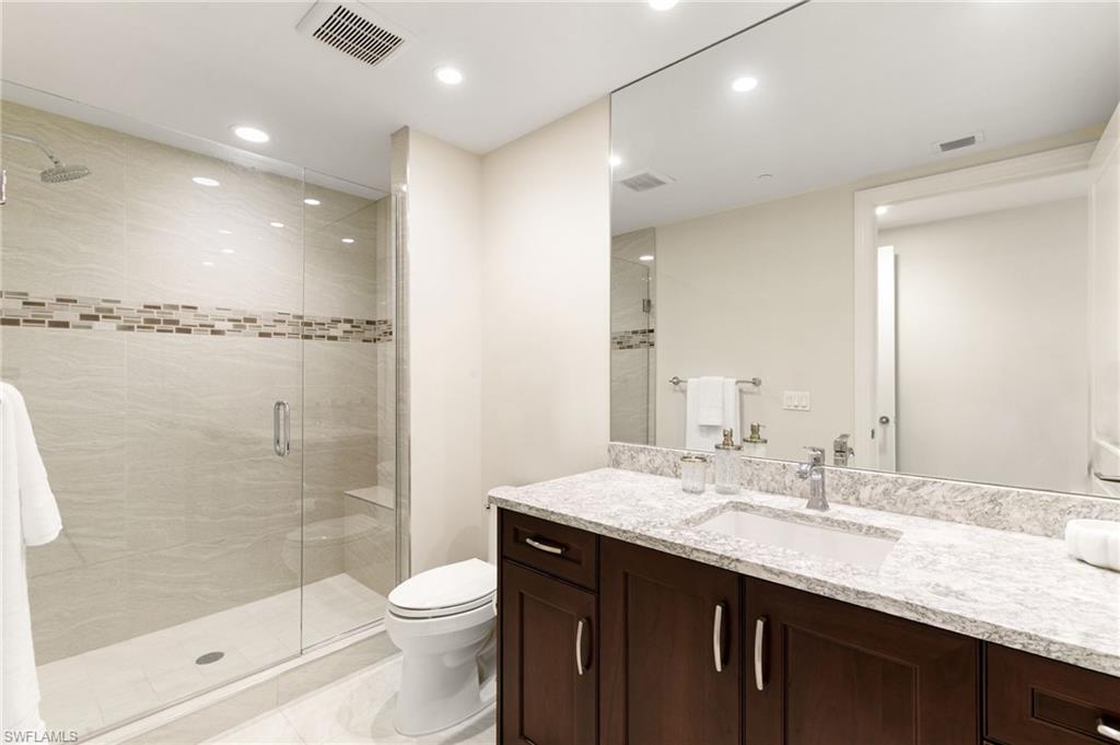 Additional full Bath with an enclosed walk-in shower, vanity, tile patterned floors, and toilet