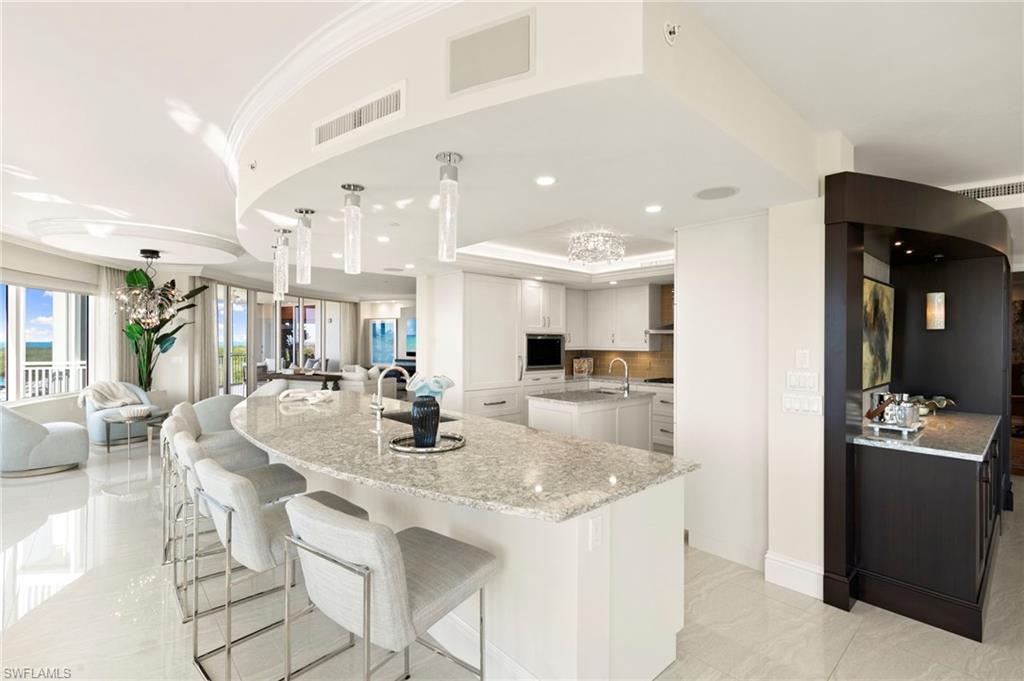 Kitchen featuring sink, custom cabinetry, smicrowave, pendant lighting, and light Quartz countertops