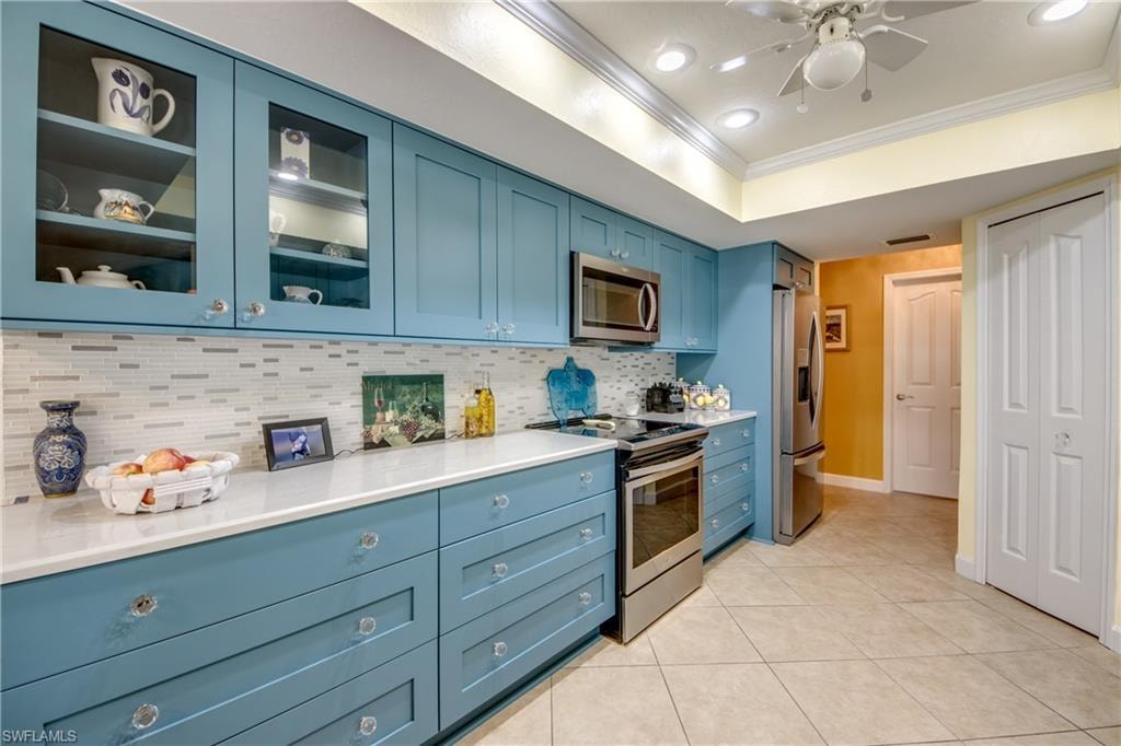 Kitchen featuring backsplash, blue cabinets, stainless steel appliances, and ornamental molding