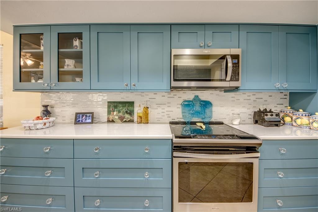Kitchen featuring decorative backsplash, appliances with stainless steel finishes, and blue cabinets