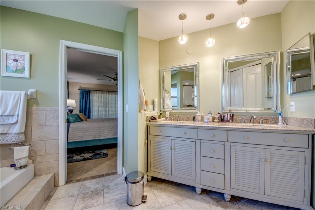 Bathroom with tile patterned flooring, ceiling fan, tile walls, and vanity