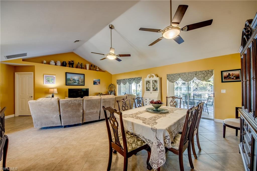 Dining space with ceiling fan, light tile patterned floors, and vaulted ceiling