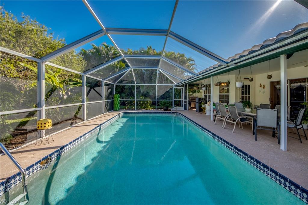 View of swimming pool with a patio area, ceiling fan, and glass enclosure