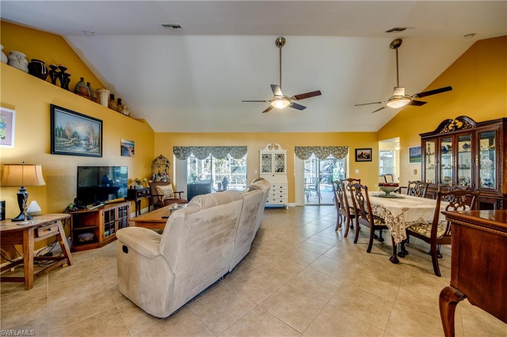 Tiled living room with ceiling fan and lofted ceiling
