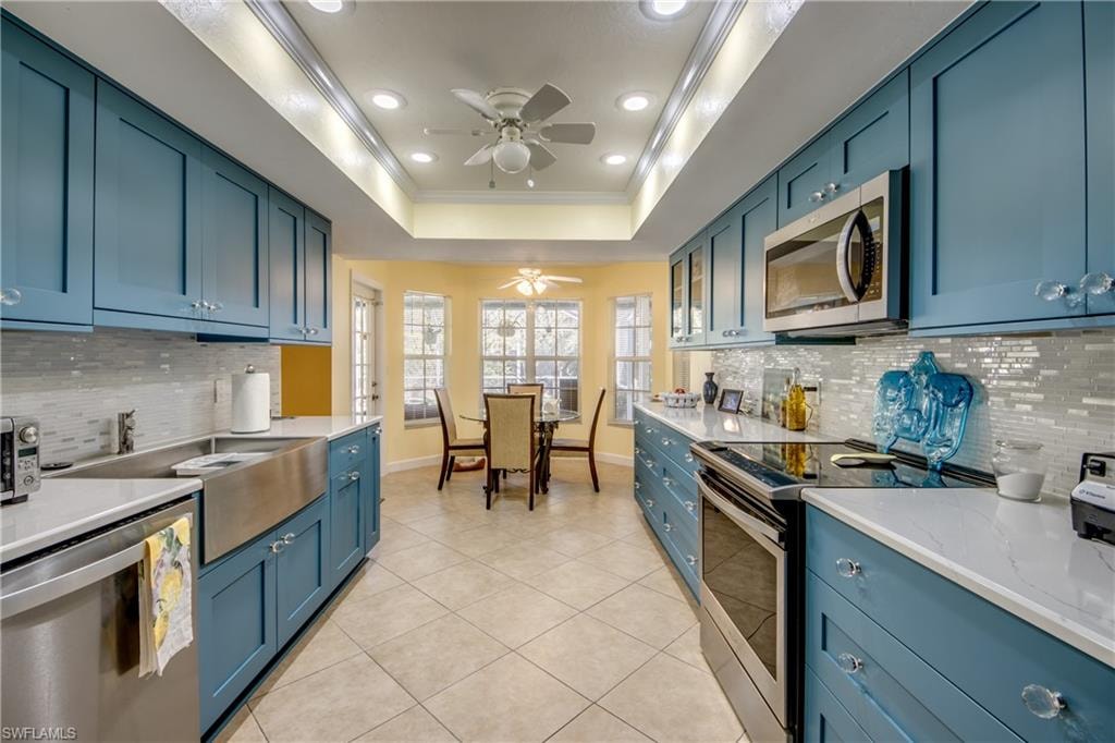 Kitchen with backsplash, light tile patterned floors, ornamental molding, and appliances with stainless steel finishes