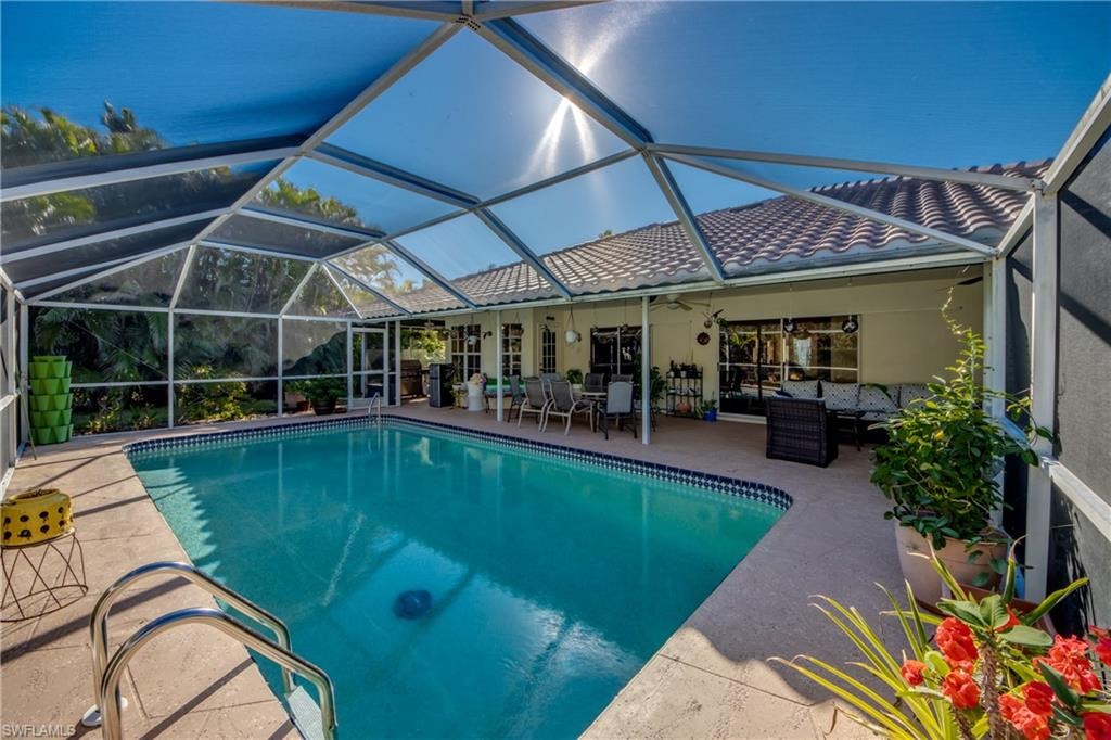 View of pool with an outdoor living space, a patio area, ceiling fan, and a lanai