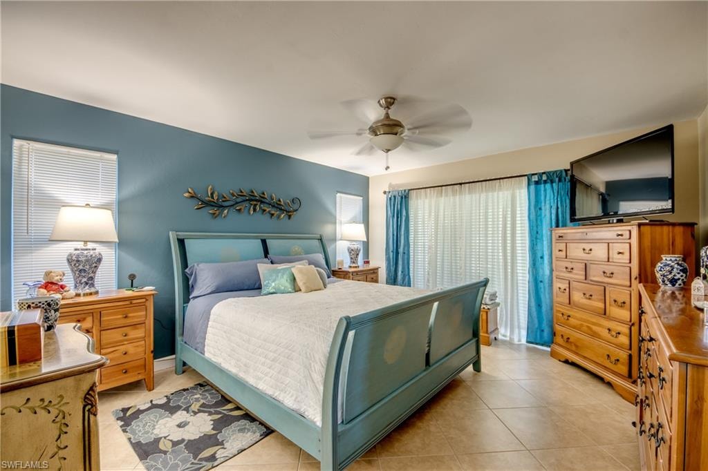 Bedroom featuring ceiling fan, light tile patterned flooring, and multiple windows