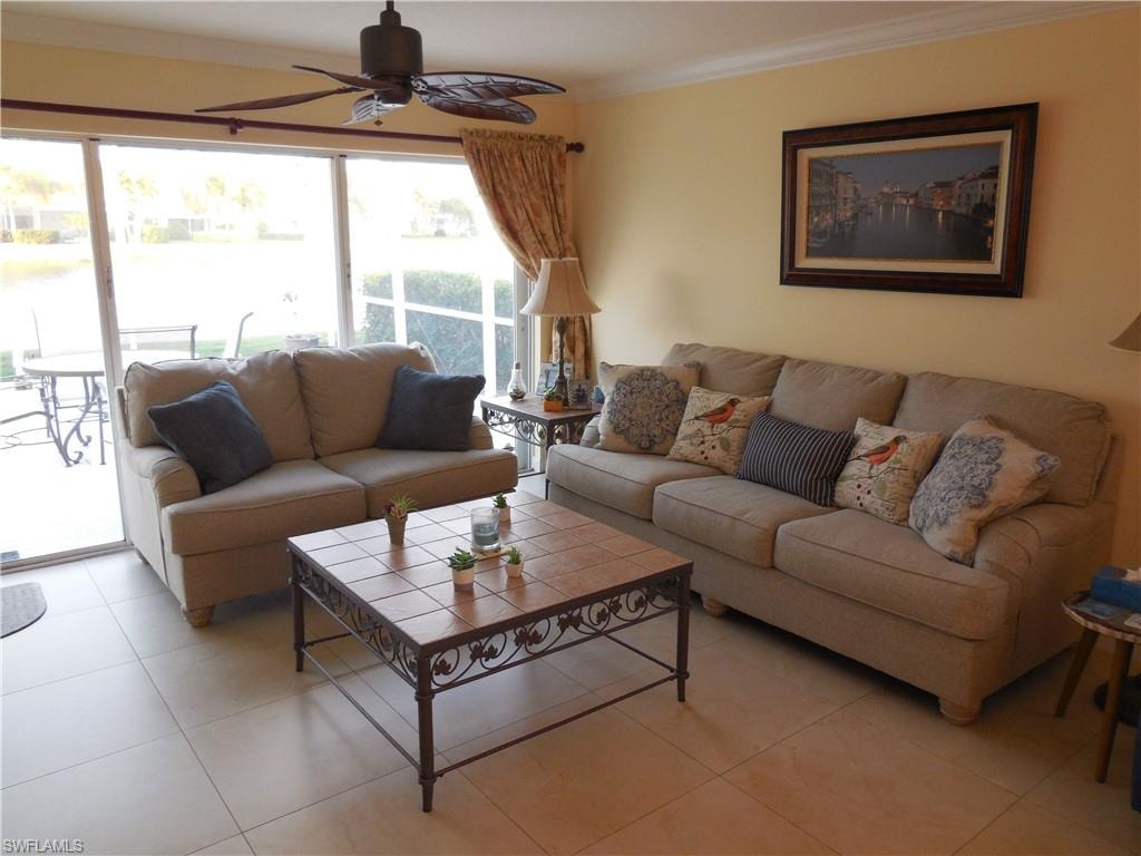 Living room featuring crown molding, ceiling fan, and light tile patterned floors