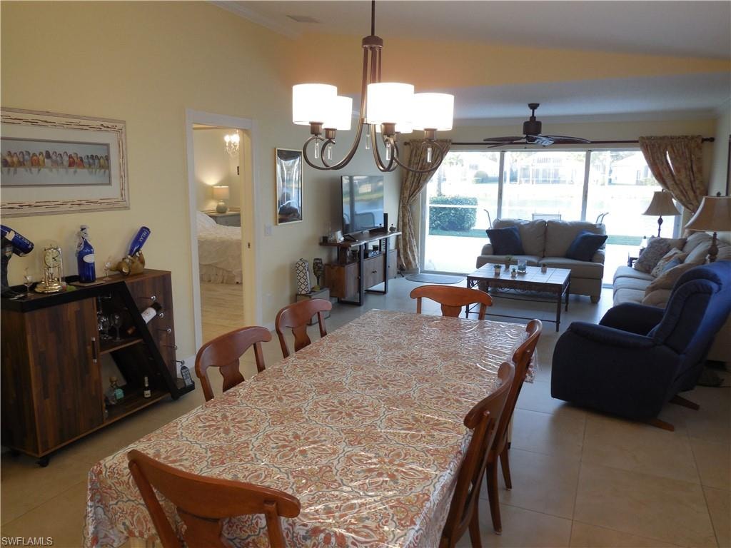 Dining room with crown molding, ceiling fan with notable chandelier, and light tile patterned floors