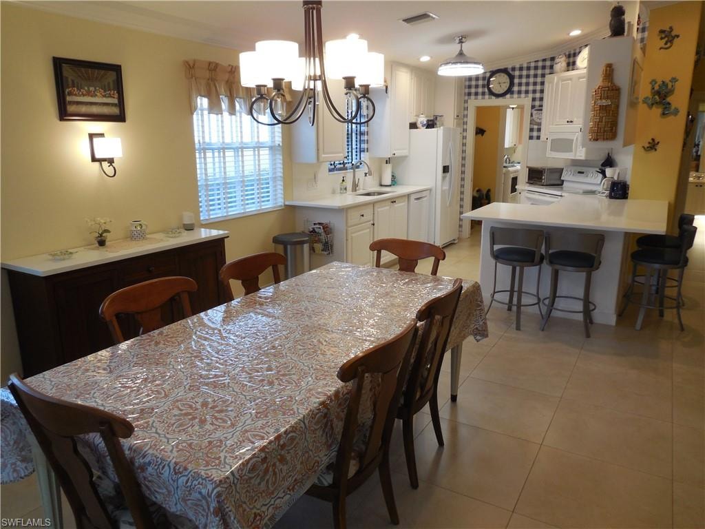 Dining space featuring sink, an inviting chandelier, ornamental molding, and light tile patterned floors