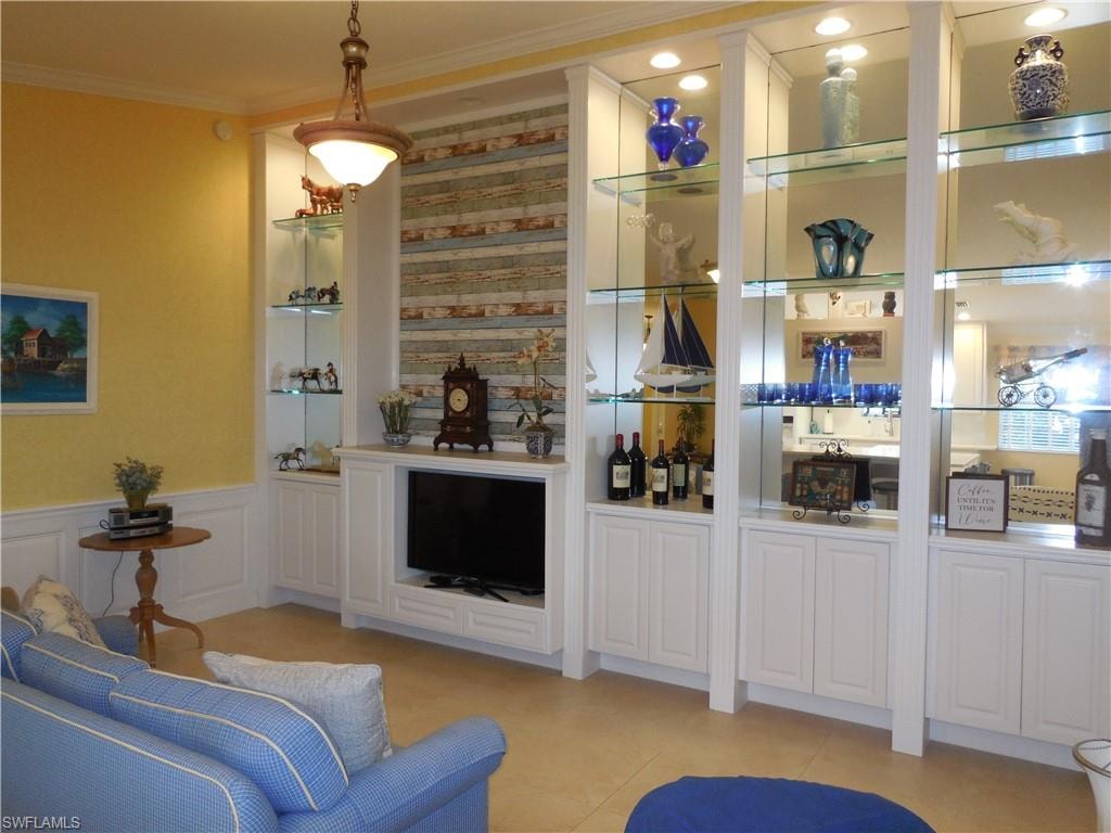 Bar with white cabinets, light tile patterned floors, hanging light fixtures, built in shelves, and crown molding