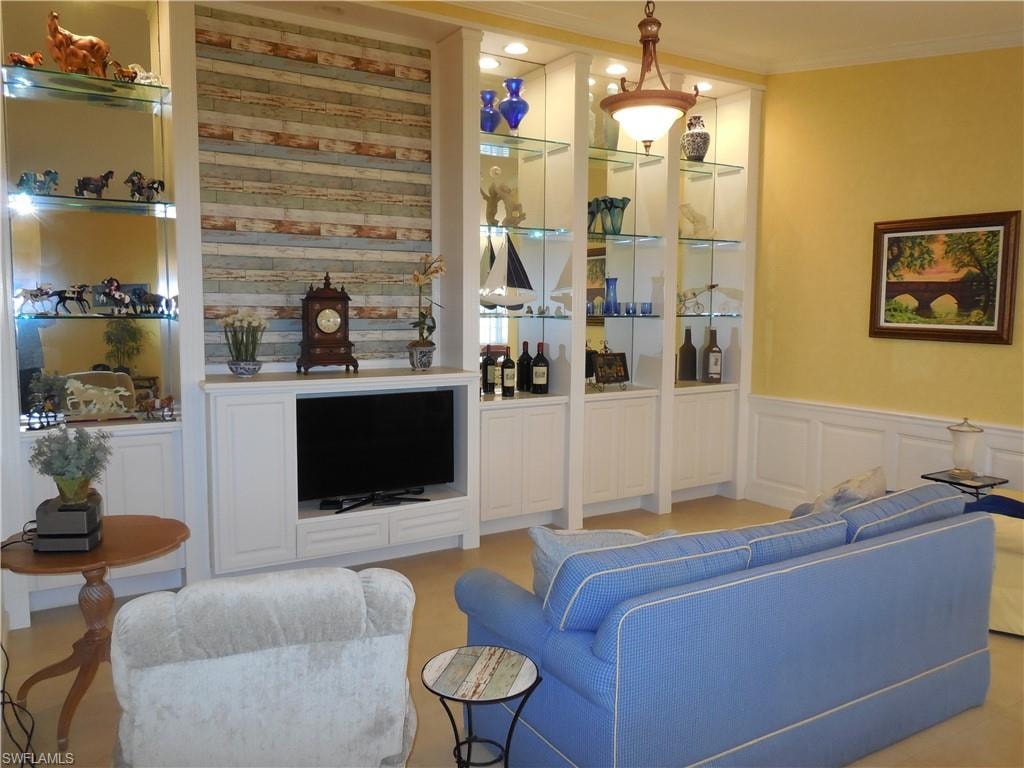 Bar with white cabinetry, hanging light fixtures, and crown molding