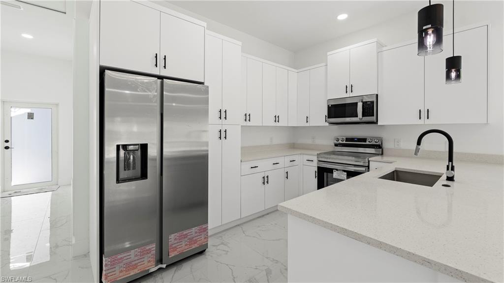 Kitchen with stainless steel appliances, light stone counters, decorative light fixtures, white cabinetry, and light marble finish flooring