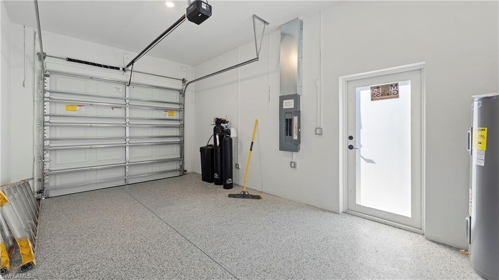 Garage featuring electric water heater, electric panel, and a garage door opener