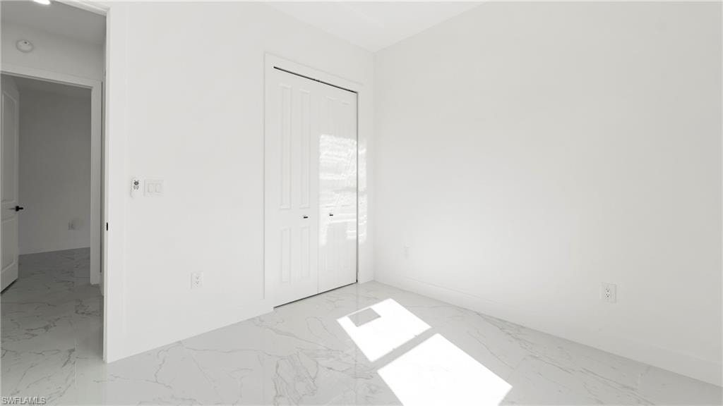 Unfurnished bedroom with a closet and light marble finish flooring