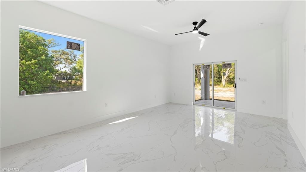 Unfurnished room with a ceiling fan and light marble finish flooring
