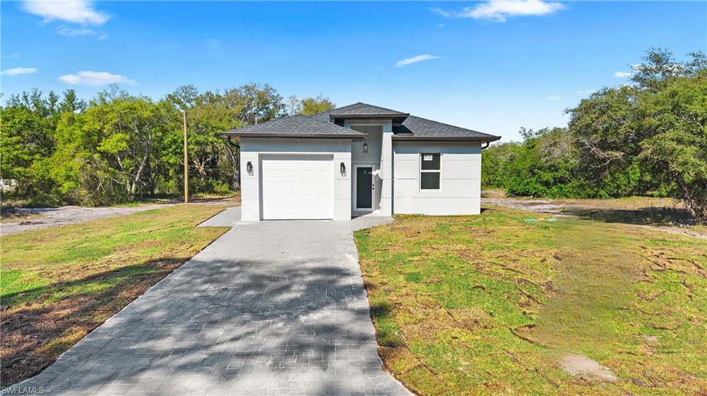 View of front facade with a front yard, driveway, an attached garage, and stucco siding