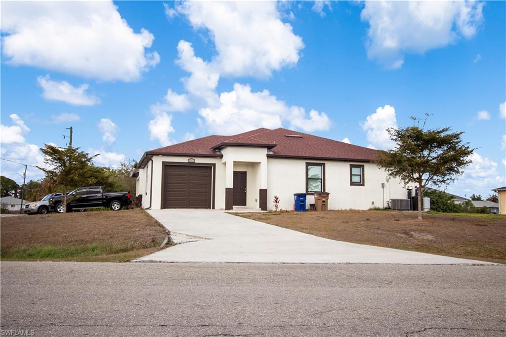 View of front of property featuring stucco siding, a garage, and driveway