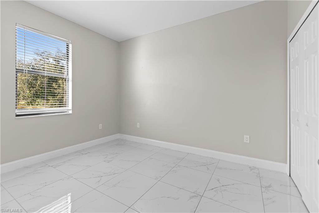 Unfurnished bedroom featuring light marble finish flooring and a closet