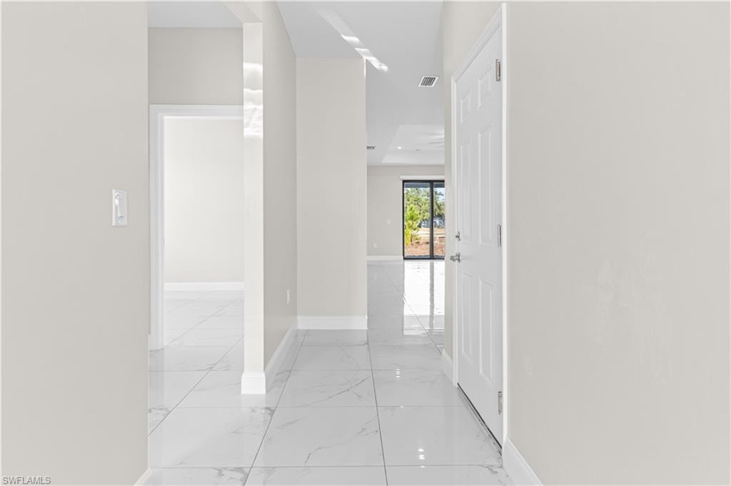 Hallway with baseboards and light marble finish floors