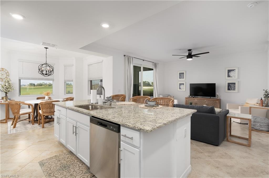 Kitchen with crown molding, a kitchen island with sink, dishwasher, and a sink