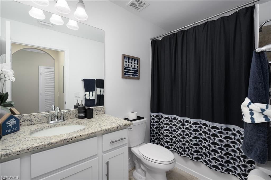 Full bath with toilet, vanity, visible vents, and a shower with curtain