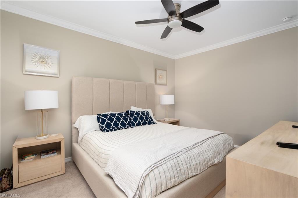 Bedroom with baseboards, ornamental molding, a ceiling fan, and light colored carpet