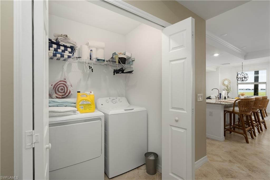 Laundry area with baseboards, laundry area, washer and clothes dryer, and crown molding