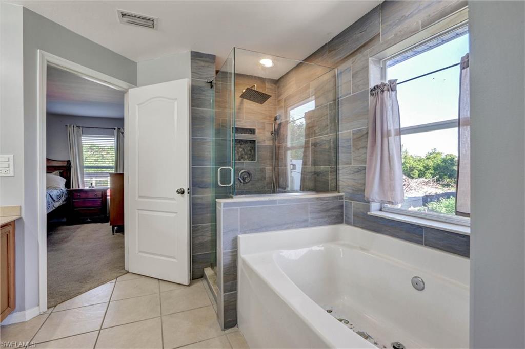 Bathroom with light tile patterned floors, a garden tub, ensuite bath, a shower stall, and vanity