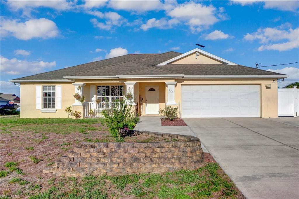 Ranch-style house with covered porch, stucco siding, an attached garage, and driveway