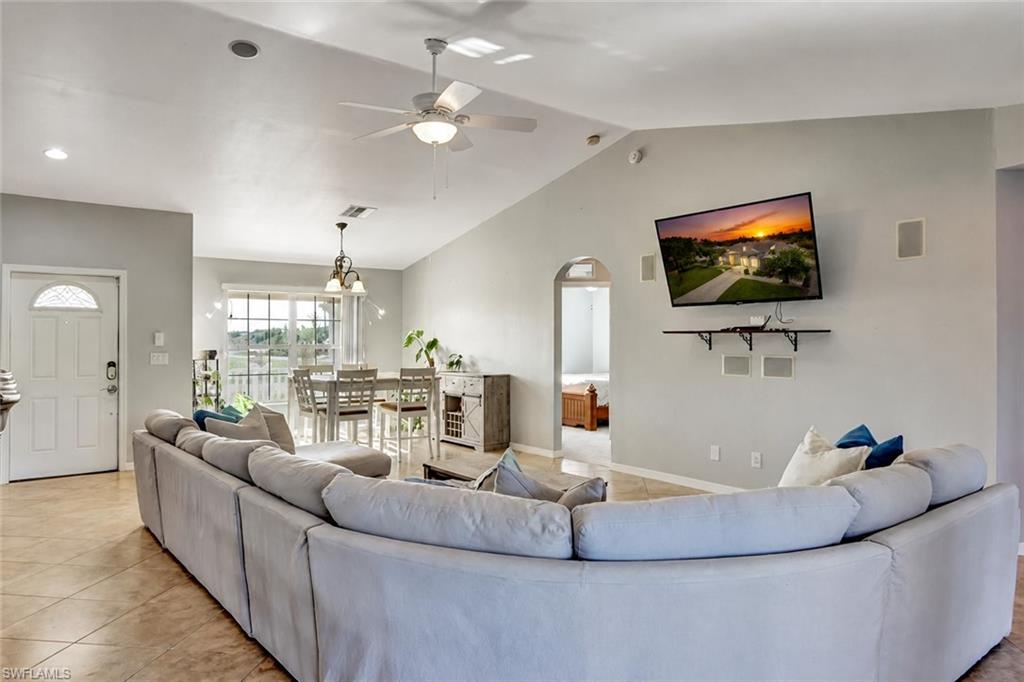 Spacious living area featuring vaulted ceilings, tile flooring, and integrated wall speakers