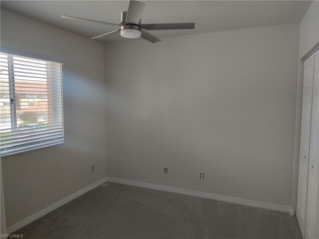 Spare room featuring a ceiling fan and dark colored carpet