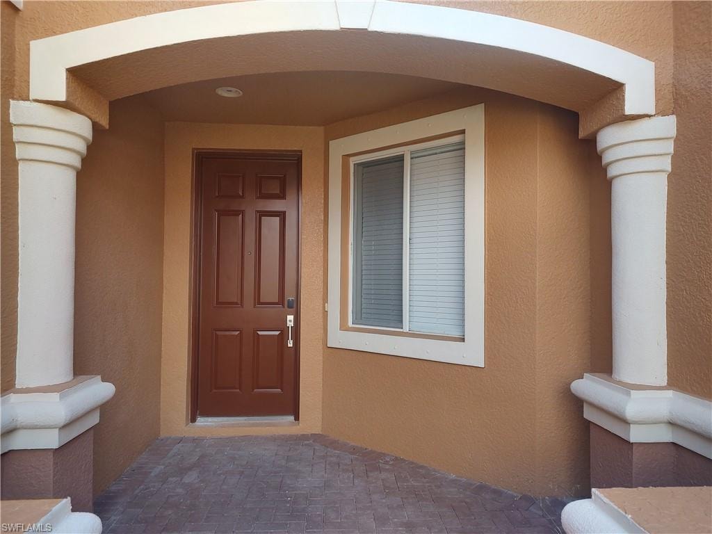 Doorway to property with stucco siding and a porch