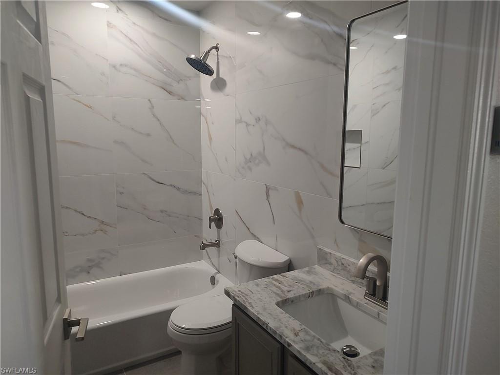 Bathroom with vanity, bathtub / shower combination, and tile walls