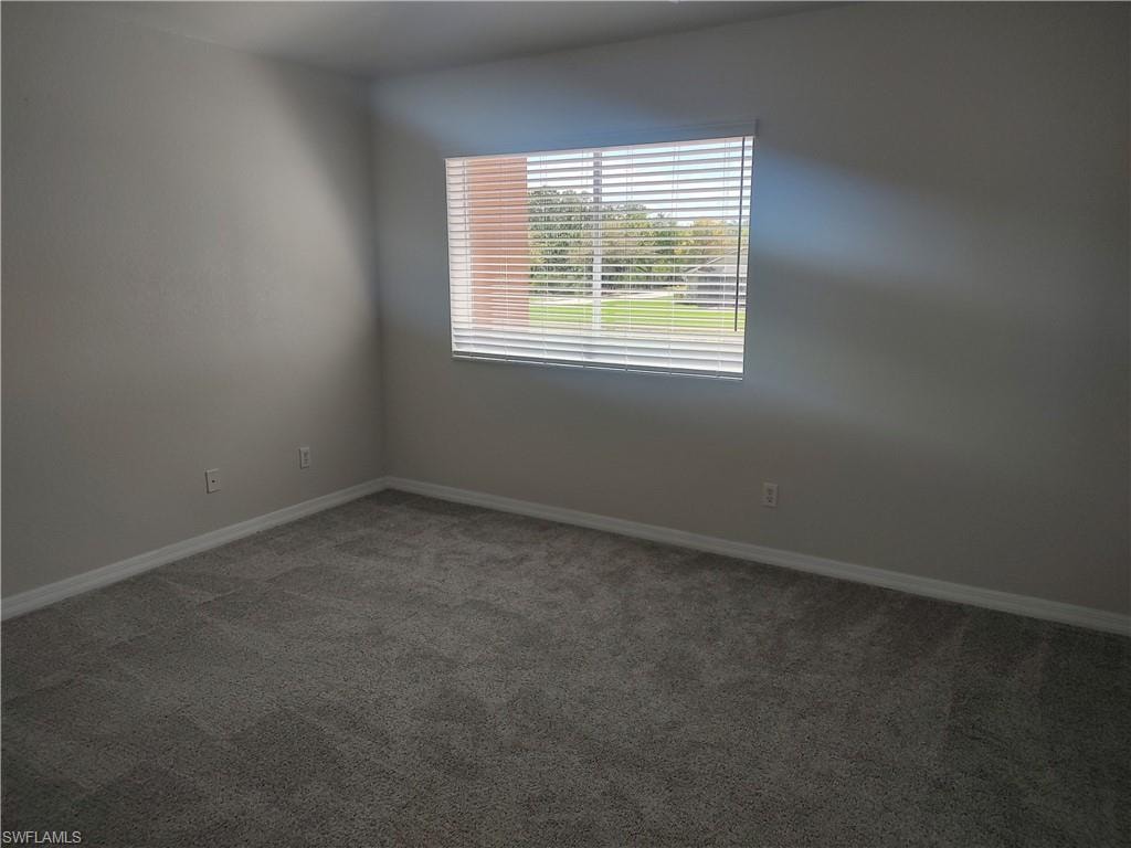 Carpeted spare room featuring baseboards
