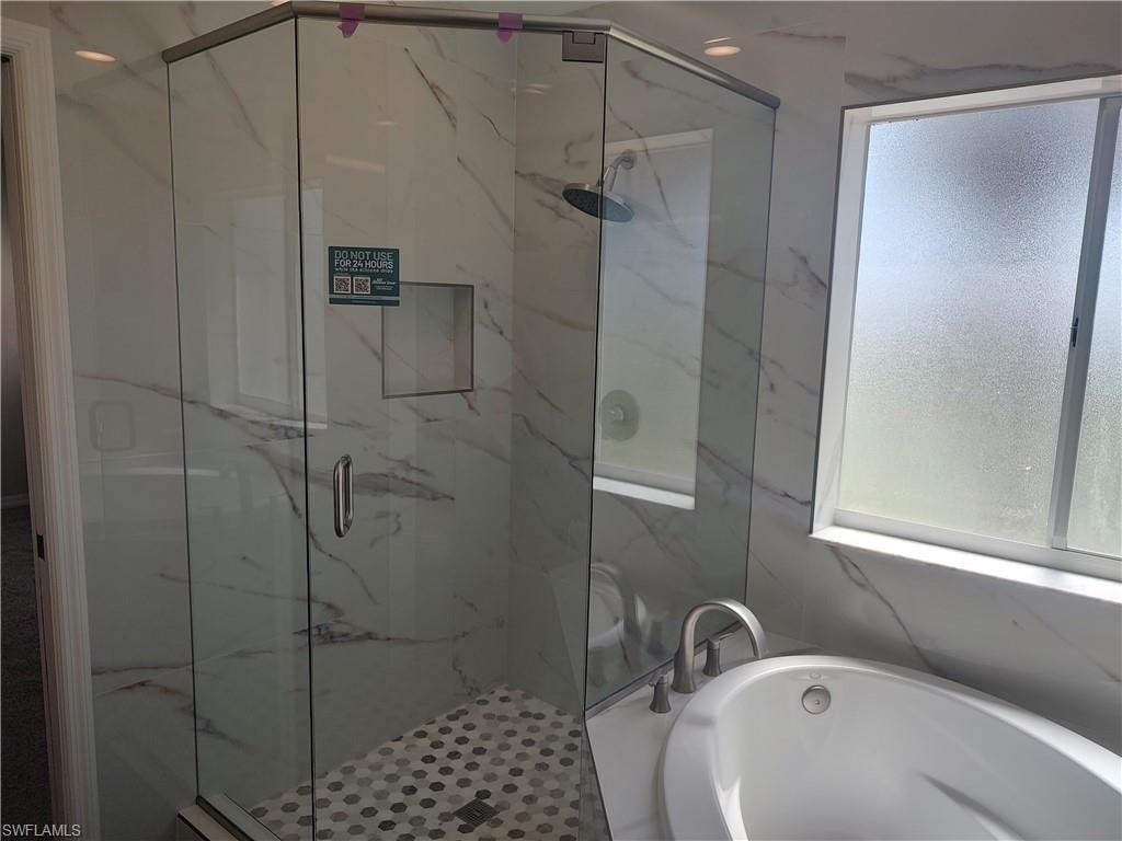 Beautifully remodeled bath featuring a garden tub and a marble finish shower