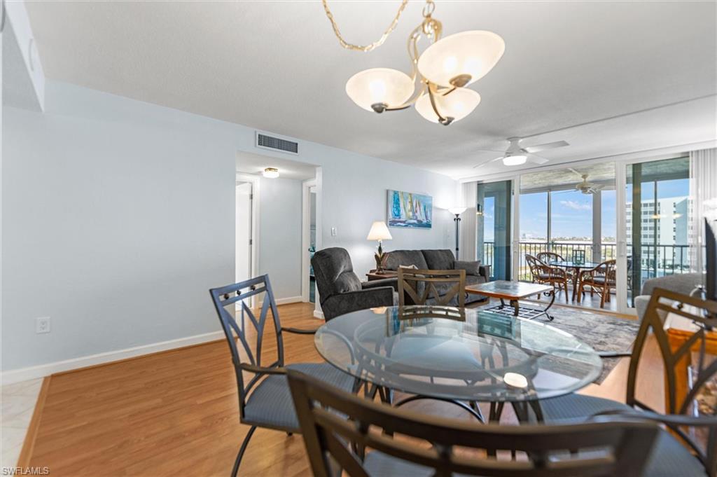 Dining area featuring ceiling fan, expansive windows, light wood-type flooring, and hanging lights