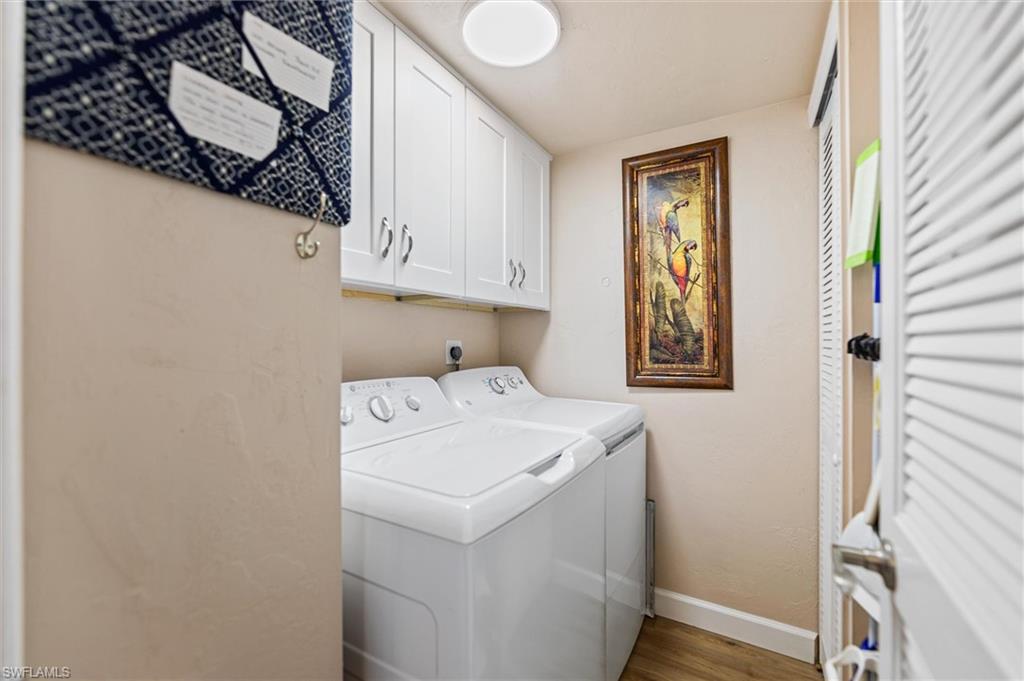 Laundry room featuring cabinet space, washing machine and clothes dryer, and light wood-type flooring