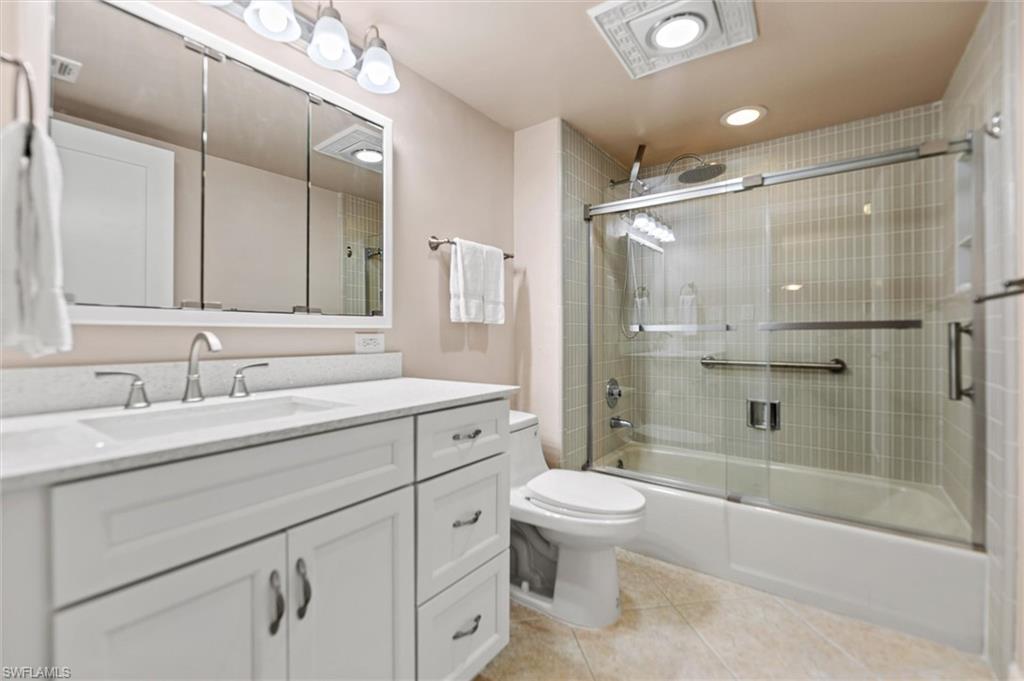 Full bathroom with vanity, bath / shower combo with glass door, and light tile patterned flooring