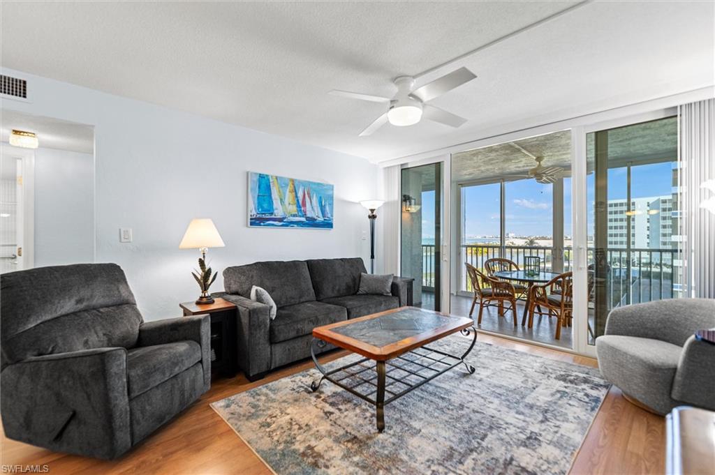 Living area with floor to ceiling windows, wood finished floors, a textured ceiling, and a ceiling fan