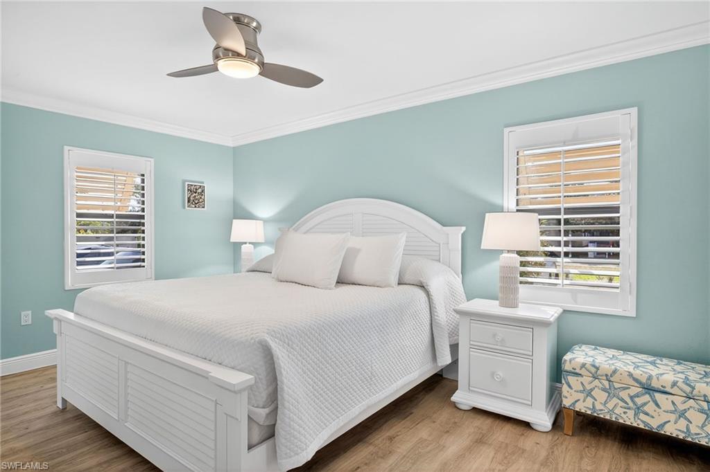 Primary Bedroom featuring light wood finished floors, ornamental molding, and a ceiling fan