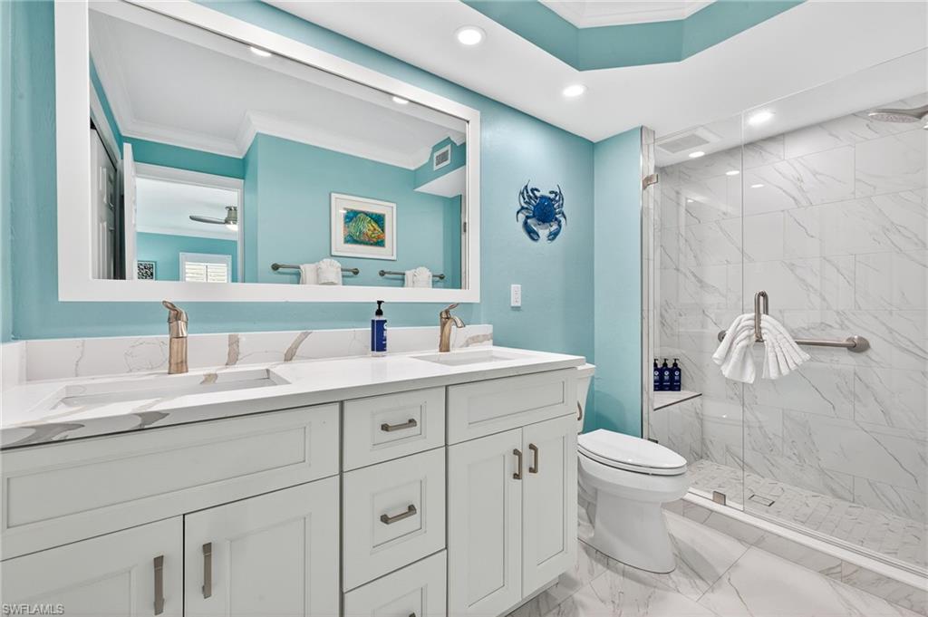 Primary Bathroom with ornamental molding, double vanity, a marble finish shower, light marble finish flooring, and recessed lighting