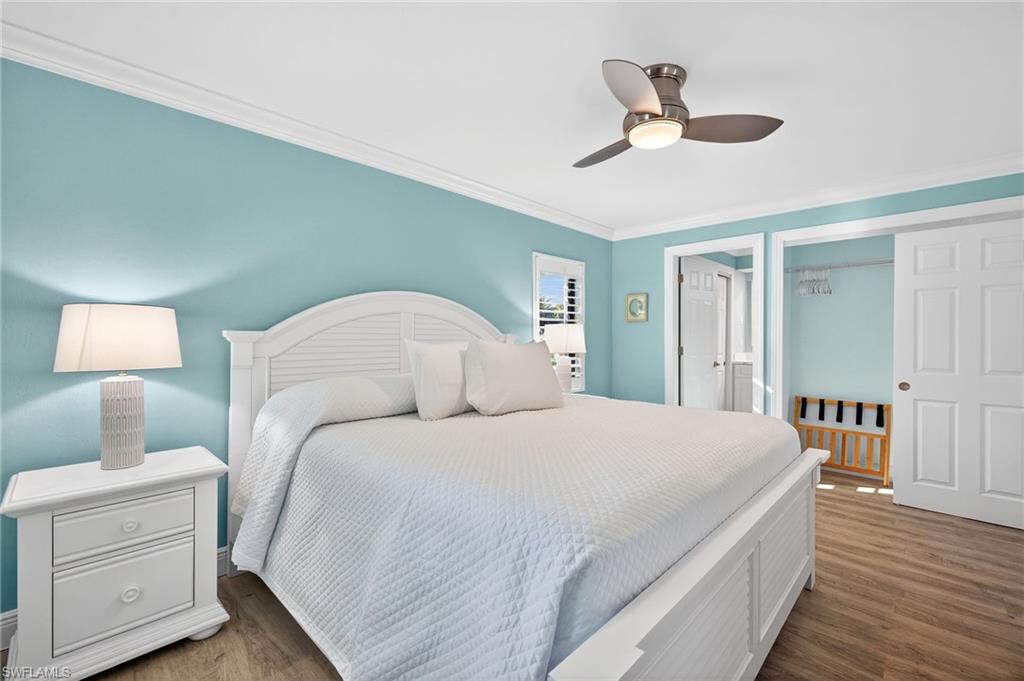 Primary Bedroom with crown molding, wood finished floors, and ceiling fan