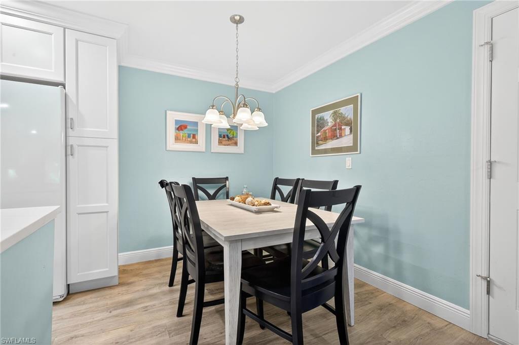 Dining space with light wood-style floors, ornamental molding, and hanging lights