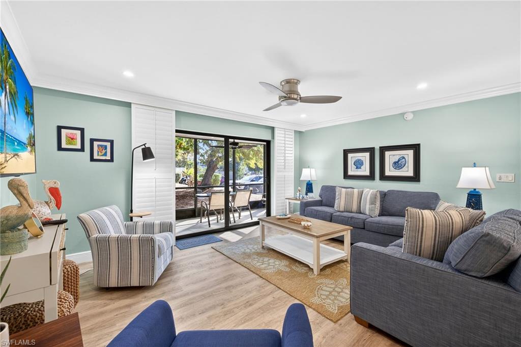 Living room with crown molding, wood finished floors, ceiling fan, and recessed lighting