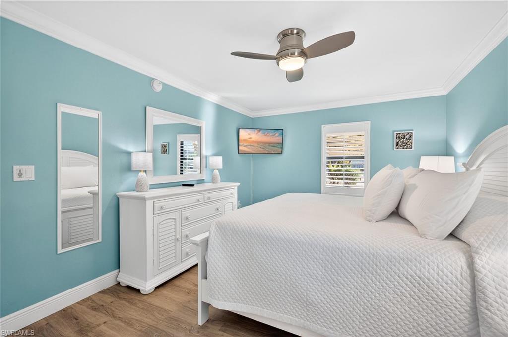 Primary Bedroom featuring light wood-type flooring, multiple windows, crown molding, and ceiling fan